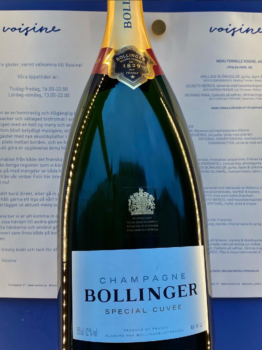 A bottle of Bollinger Champagne Special Cuvée placed on a blue surface with menus or papers in the background.