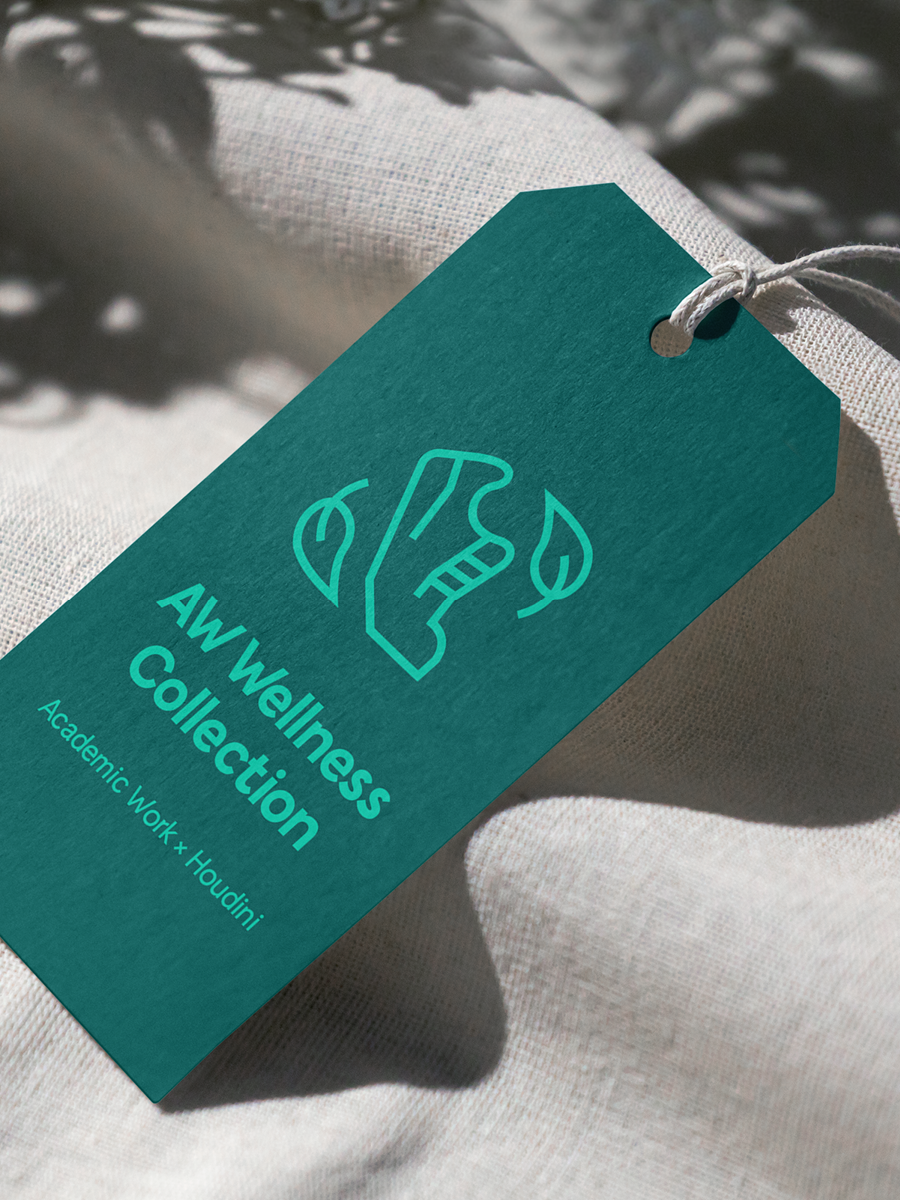 Teal-colored tag labeled "AW Wellness Collection" with a line drawing of a foot and leaves, attached to fabric, with shadows from nearby foliage.