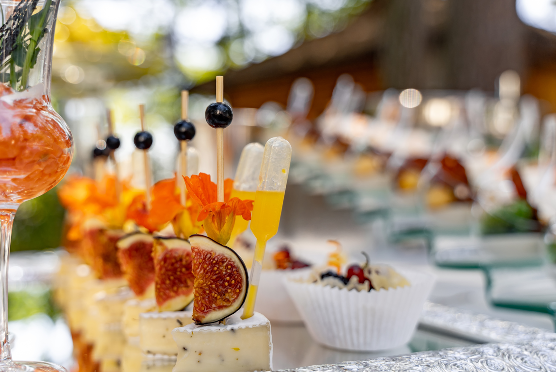 Scenic view of a lake with turquoise water, surrounded by rolling green hills and mountain ranges under a cloudy sky.