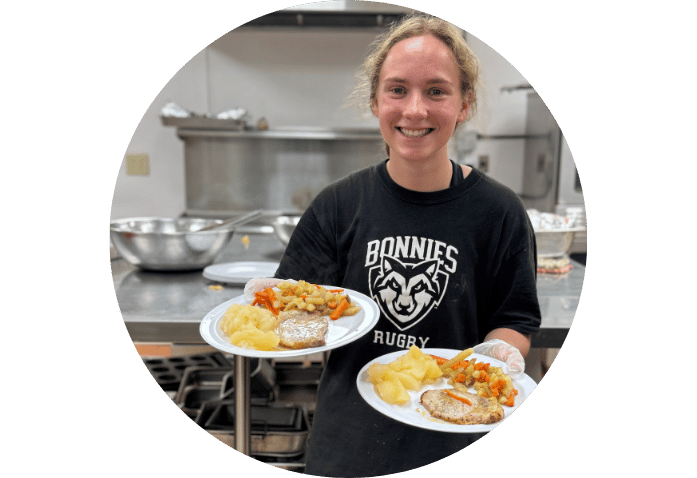 A smiling female student holds two plates of food