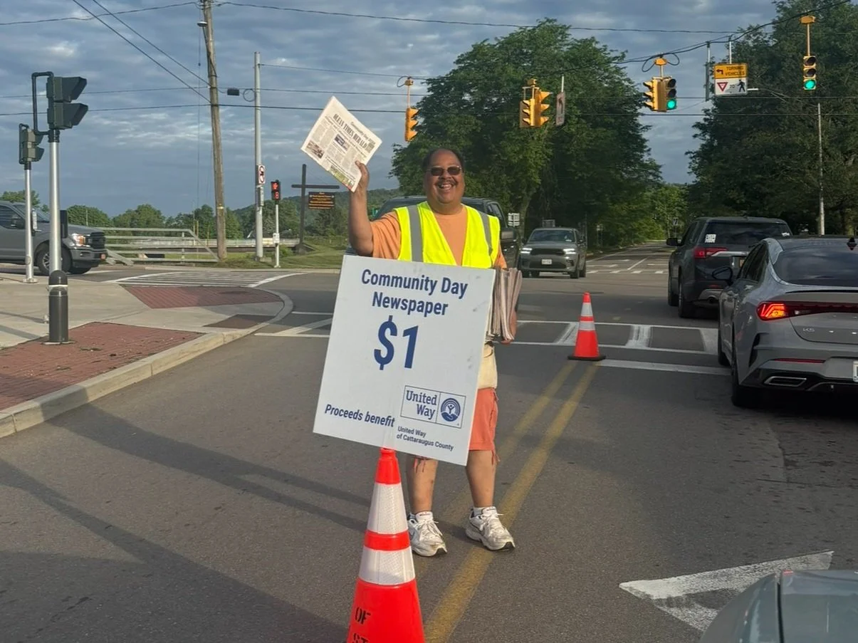 A man holds a newspaper to sell for charity.