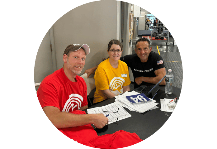 Two men and a woman smiling at a registration table