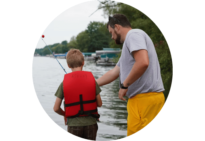 A man helps a boy to fish