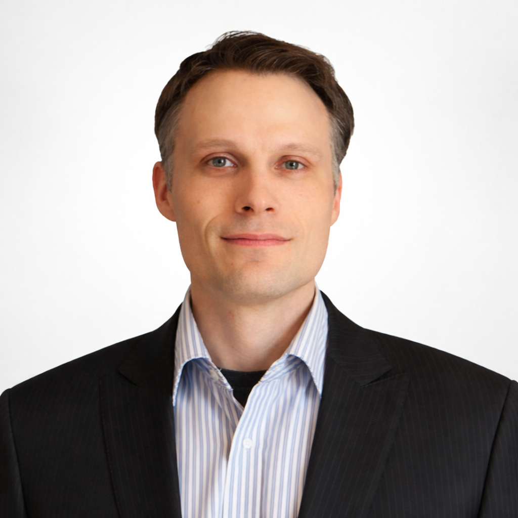 Man in a black suit with a striped shirt against a white background.