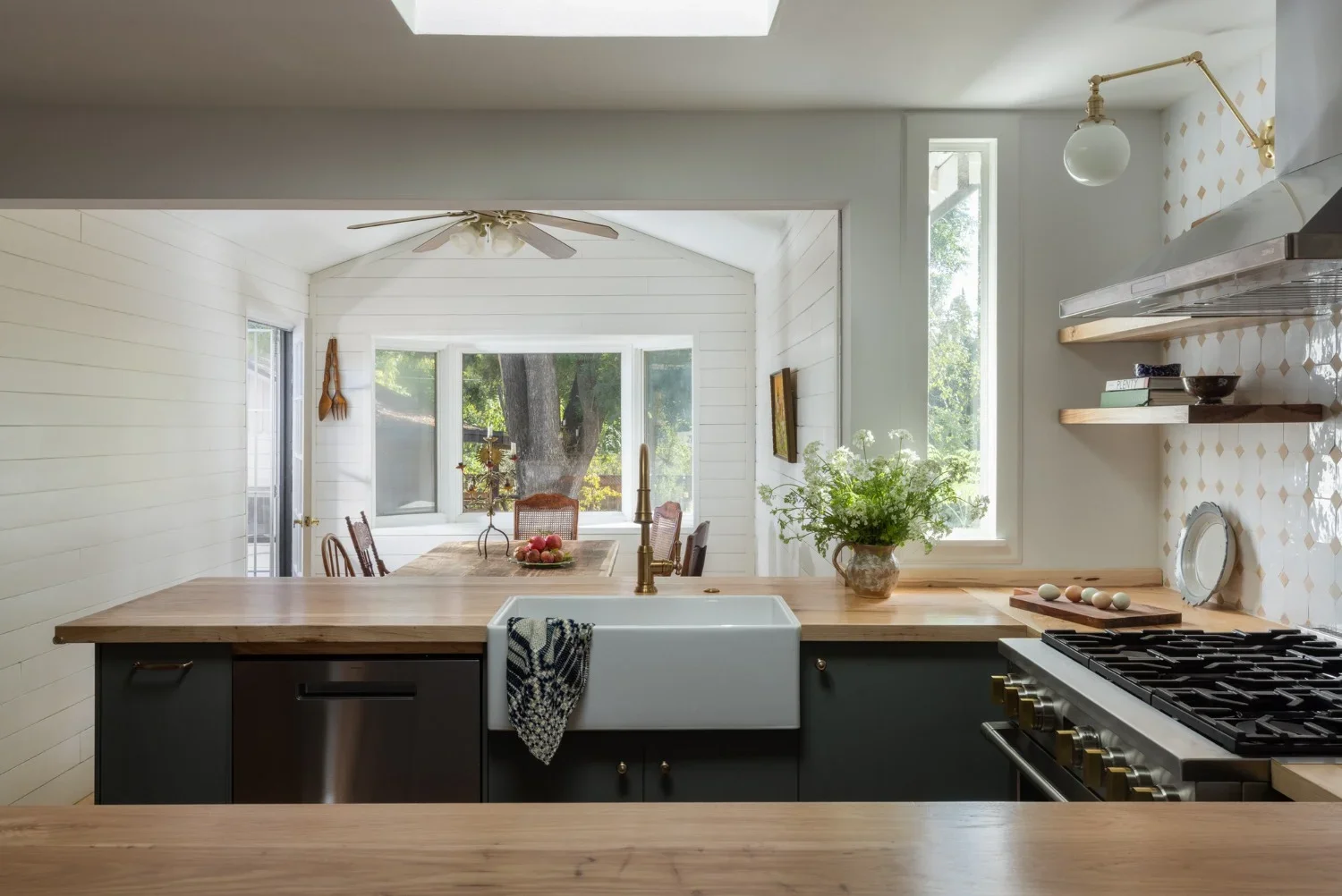 Renovated kitchen with skylight, farmhouse sink, and sage cabinetry in a Bay Area home by Studio VAE interior designers