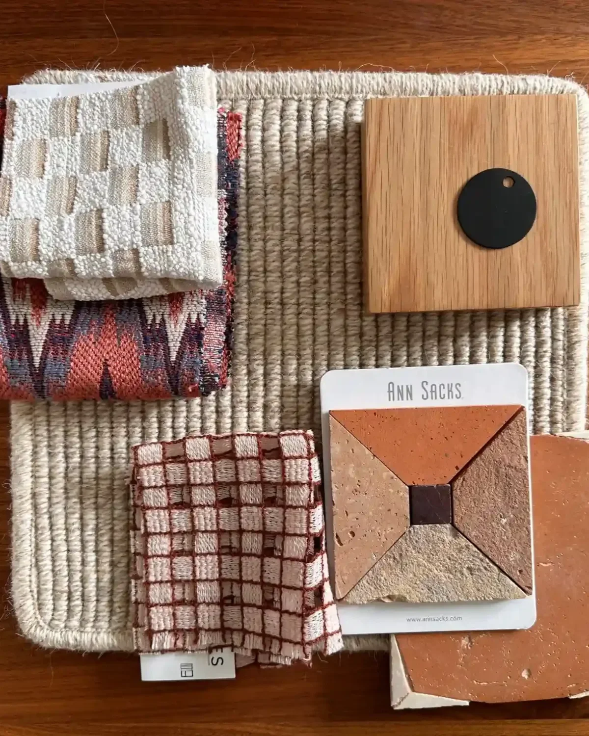 Curated material samples for a Studio VAE interior design project — wool rug, woven fabrics, Ann Sacks tile, terracotta, white oak, and matte black hardware.