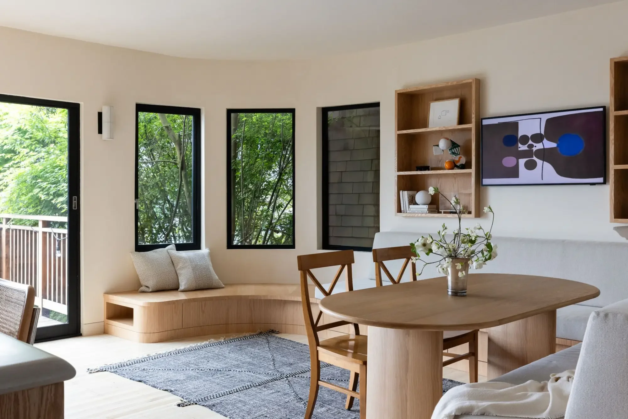 Custom curved built-in dining bench with wood table and open shelving in a Parnassus Heights home by Studio VAE, a San Francisco interior design studio