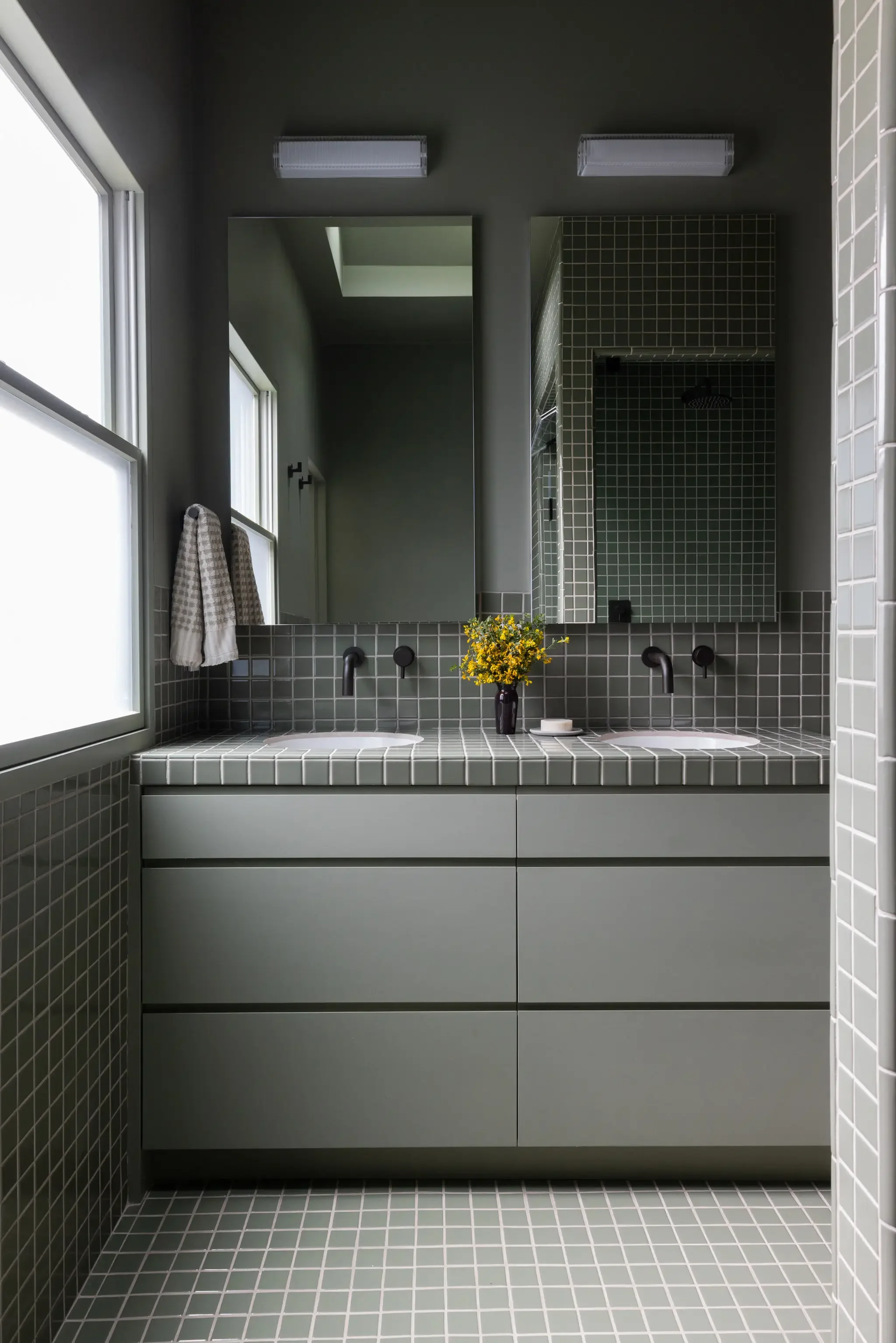 Primary bathroom with green tile, double vanity, dark brozne fixtures, and matching tiled countertop in a Parnassus Heights home designed by Studio VAE