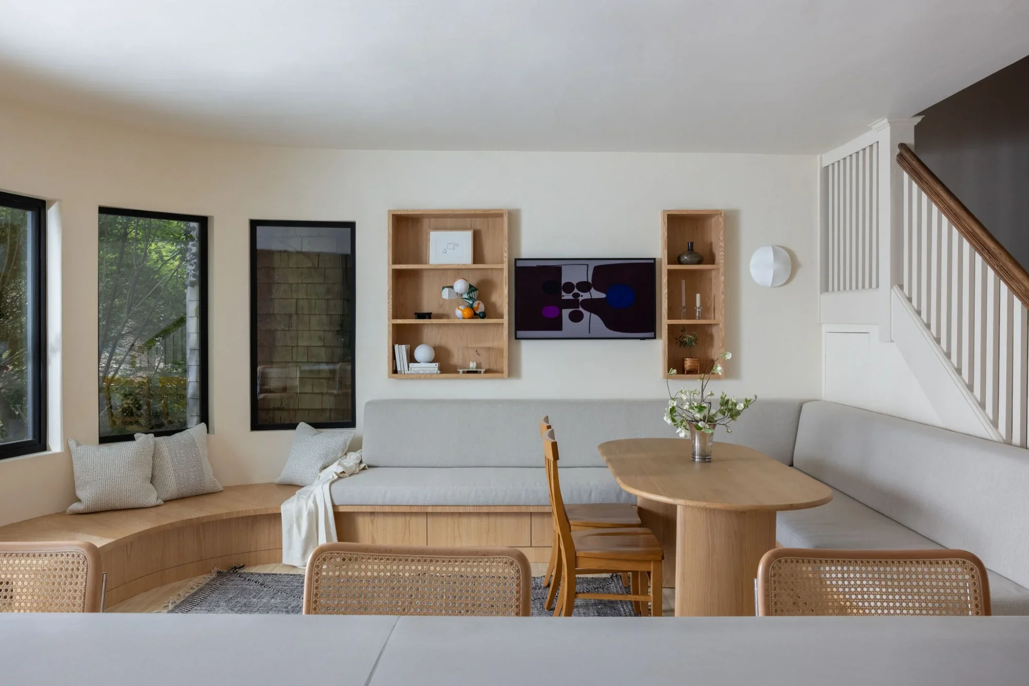 Custom curved banquette with built-in drawer storage and red oak open shelving flanking the media wall in the Parnassus Heights full home renovation, San Francisco