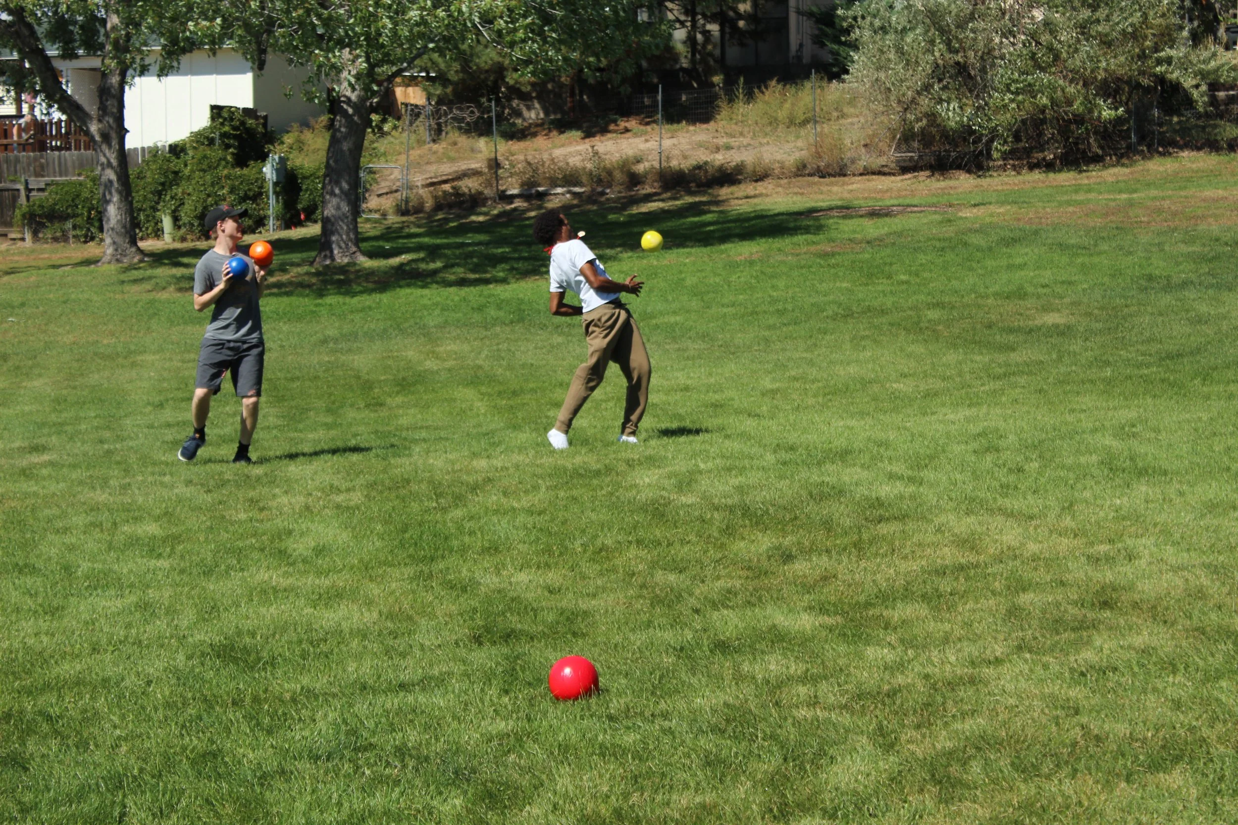 People playing dodgeball in a grassy park.