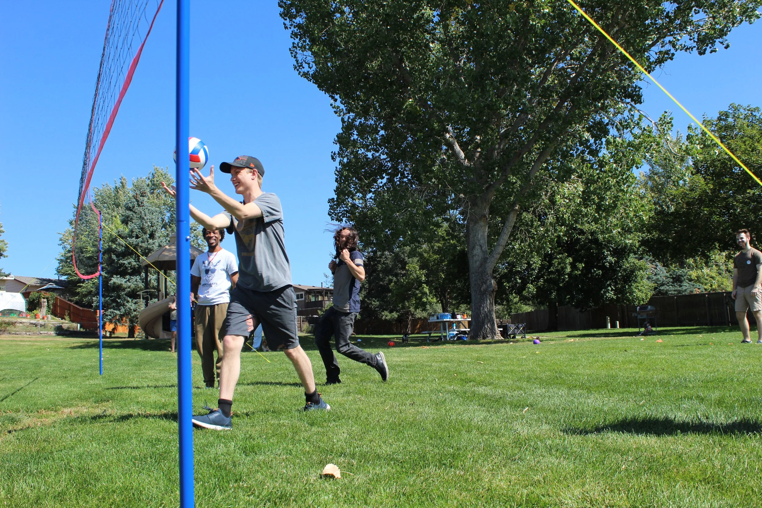 Group of people playing volleyball outdoors on a sunny day.