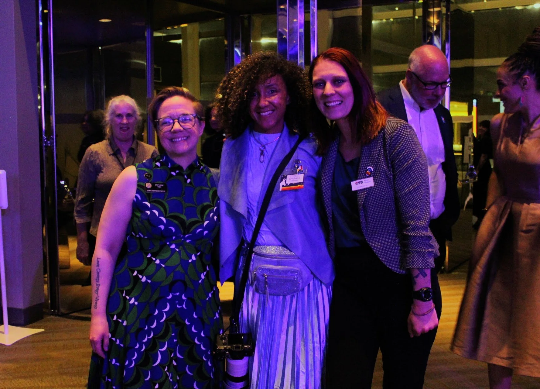 Group of people posing at an event, wearing conference badges and formal attire.