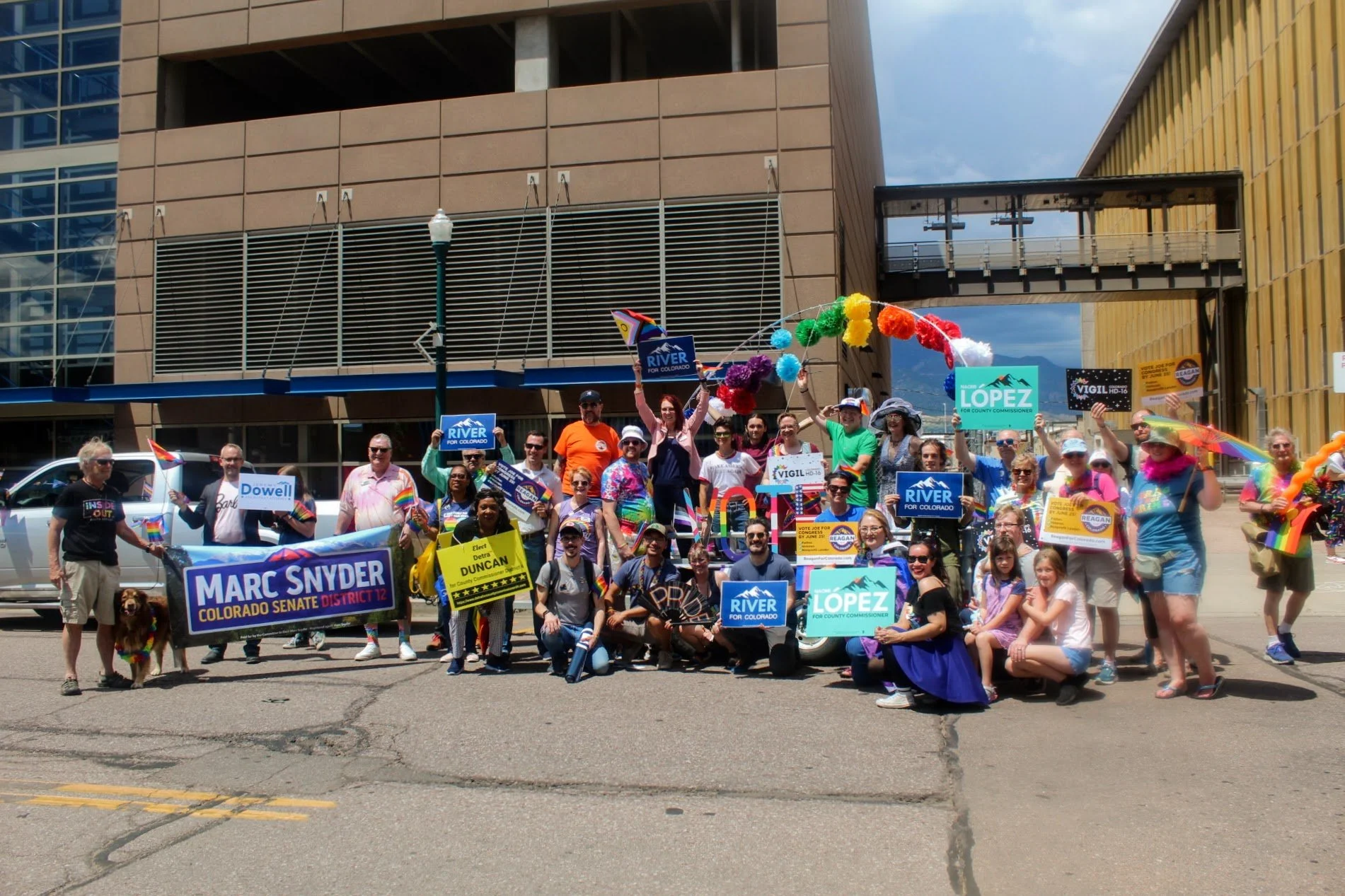 Group of people holding campaign signs at a political rally in an urban setting.
