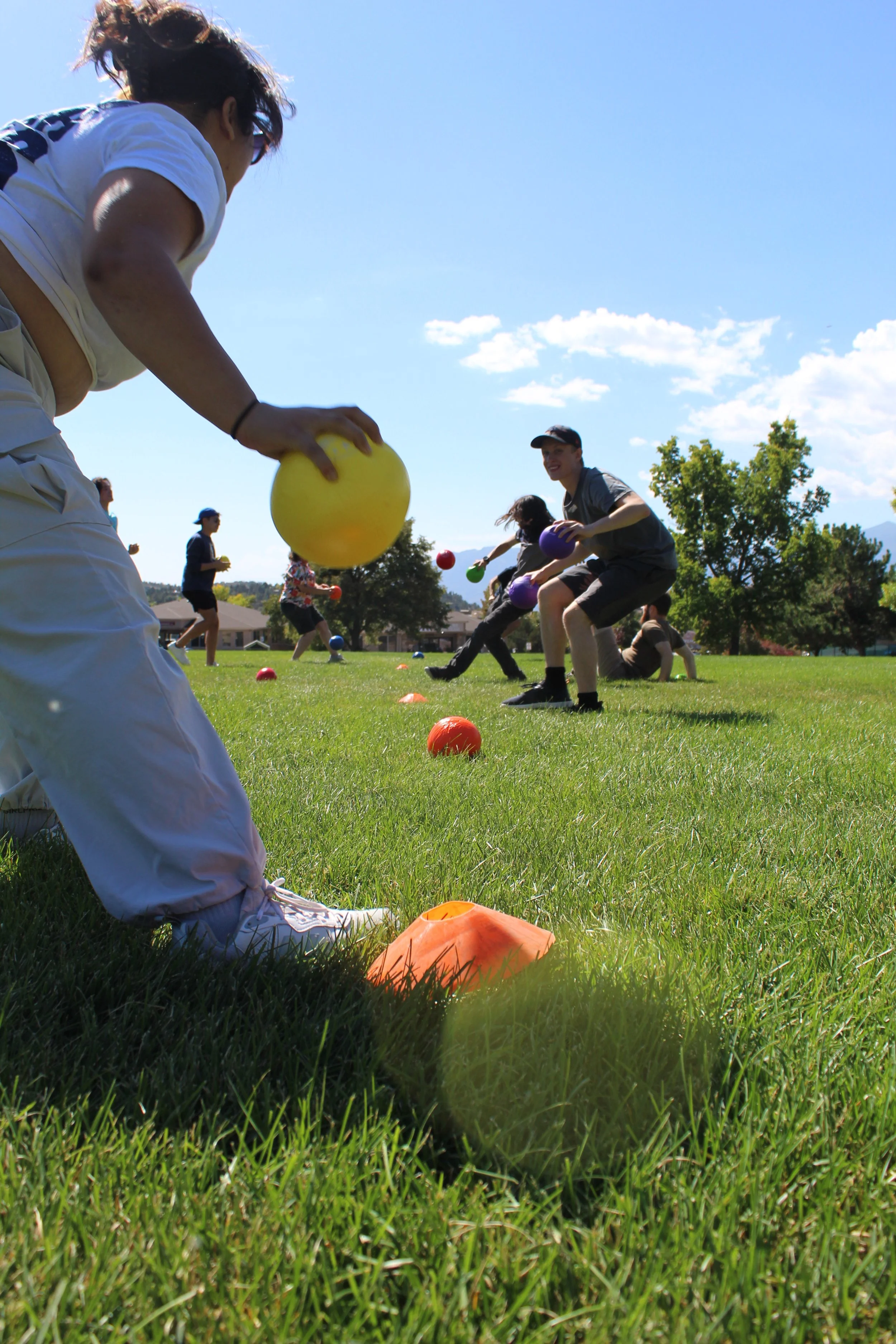 Group of people playing dodgeball on grass field