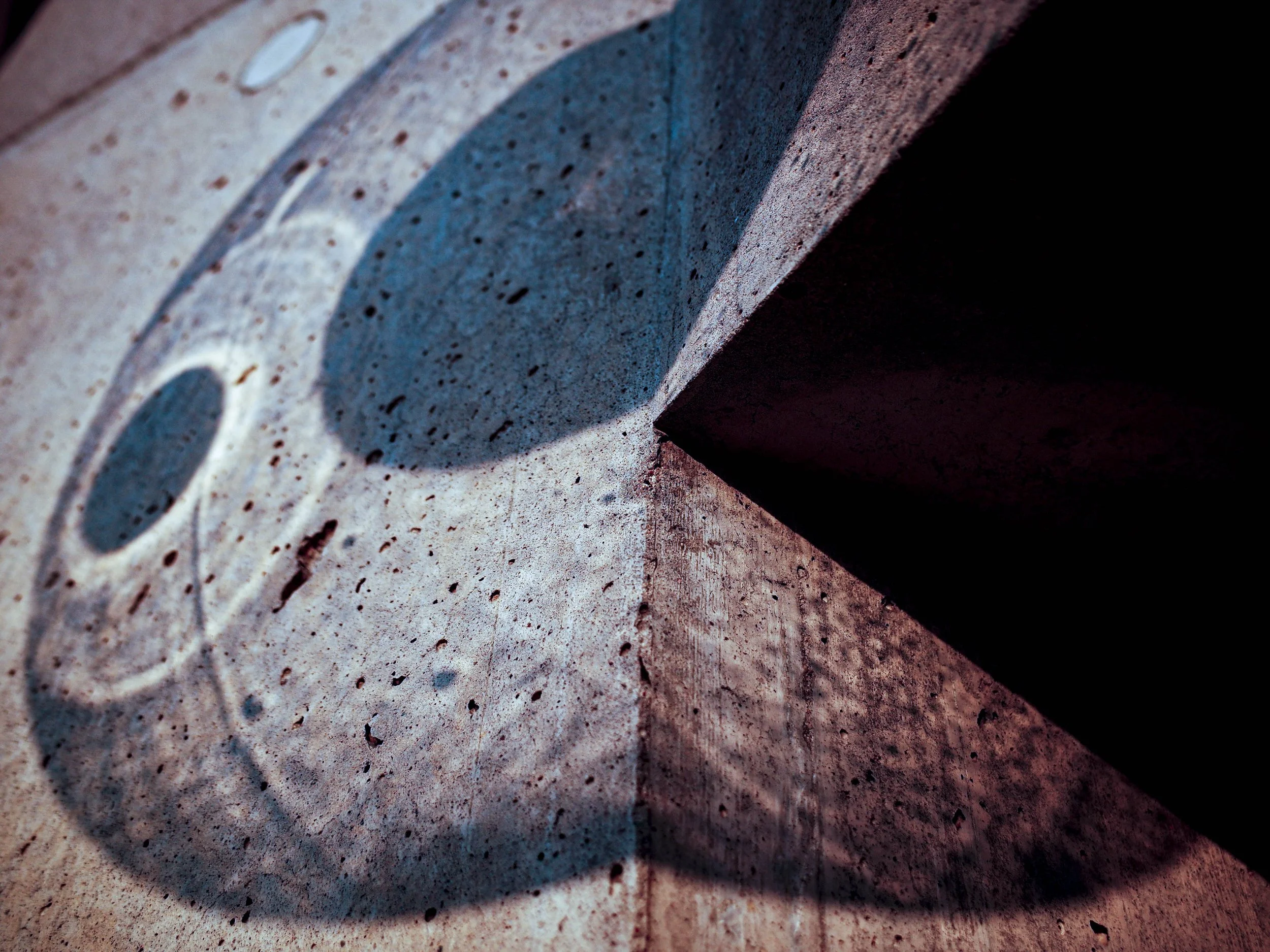 Close-up of a cardboard box positioned at an angle, casting a shadow on a speckled, reddish surface.