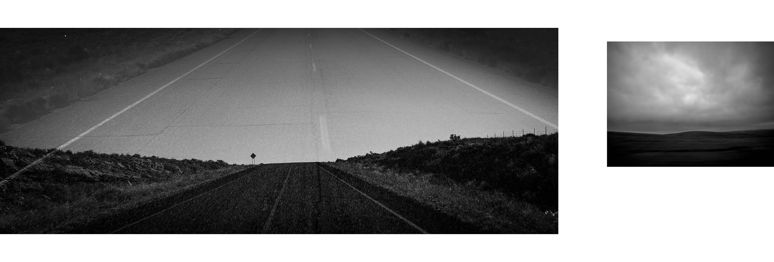 Black and white photo of an empty open road stretching into the distance with hills and cloudy sky