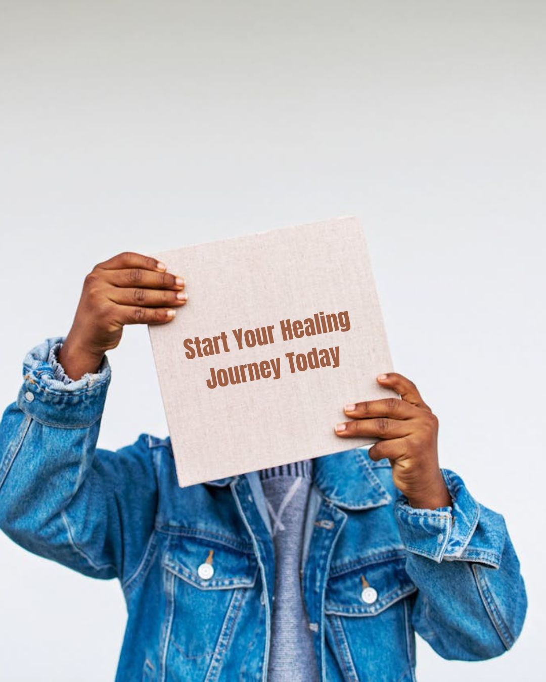 Person holding a sign that says 'Start Your Healing Journey Today' while wearing a denim jacket.