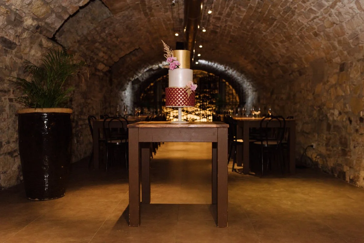 Wedding cake displayed inside the historic wine cellar at Castello del Trebbio in Tuscany.