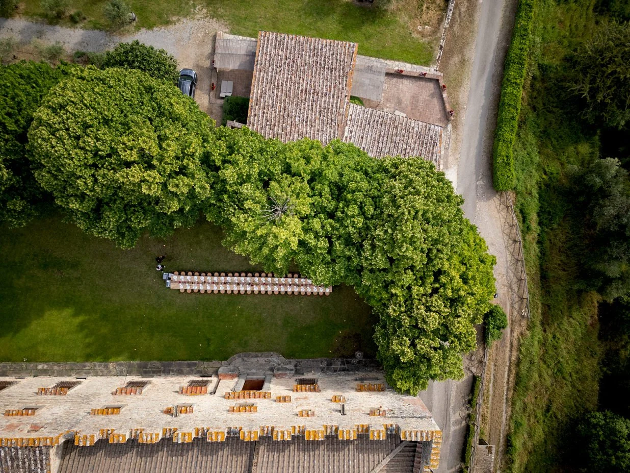 Drone view of the wedding dinner table at Castello di Meleto, showing the table layout within the courtyard and surrounding Chianti landscape in Tuscany.