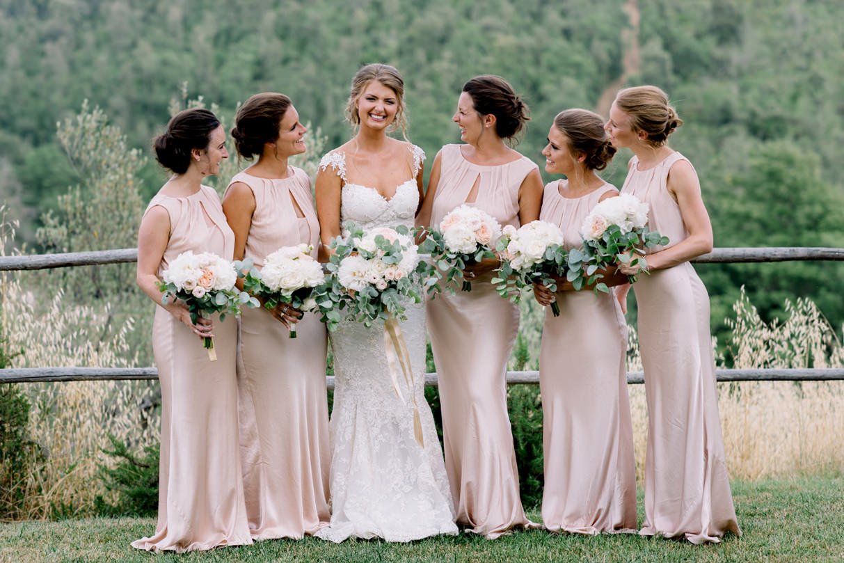 Bride smiling with her bridesmaids holding bouquets at Conti di San Bonifacio wedding venue.