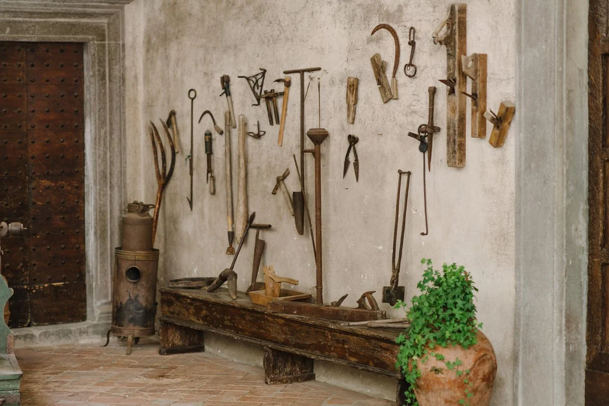Original historic tools displayed on the stone wall inside Castello del Trebbio, reflecting the estate’s agricultural history.