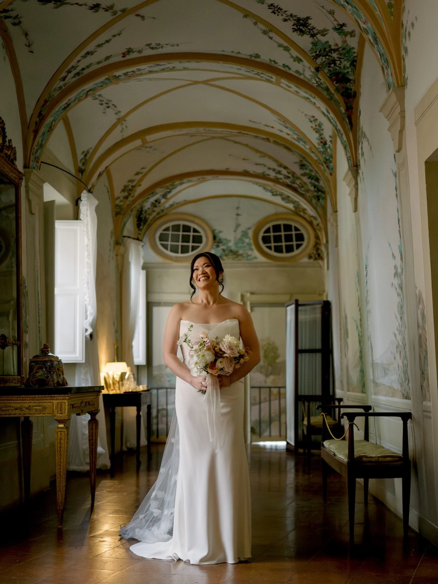 Bridal calm before the celebration. In the soft Tuscan light of Castello di Celsa, she paused for a quiet moment smiling, bouquet in hand, surrounded by the timeless beauty of this historic hallway. These intimate pauses are what make wedding photogr