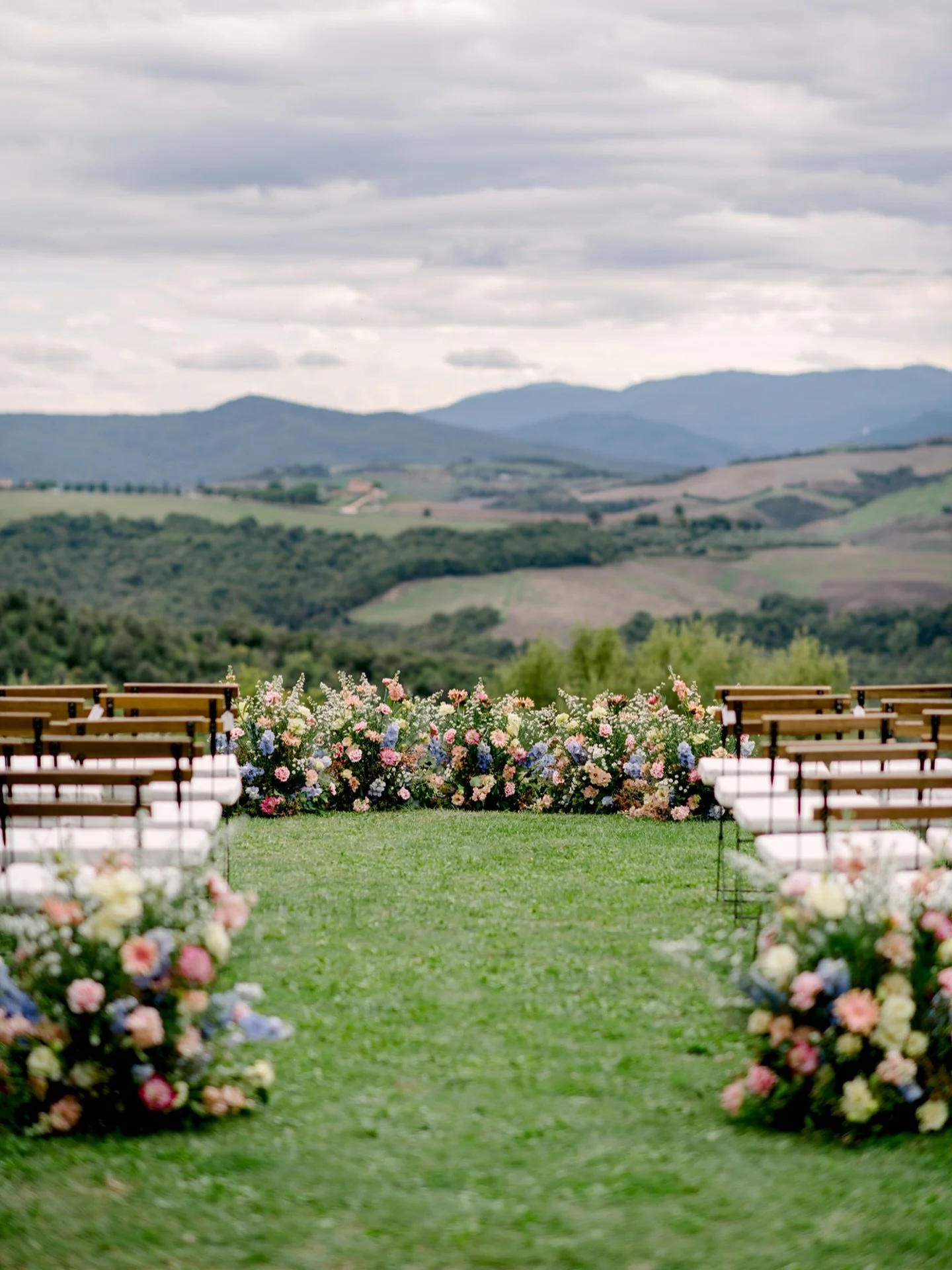 Ceremony magic at Villa di Ulignano! A sea of color under the Tuscan sky soft blues, blush pinks, peaches, and creamy blooms framing a love-filled ceremony. The floral design at Villa di Ulignano turned this moment into a living painting, every detai