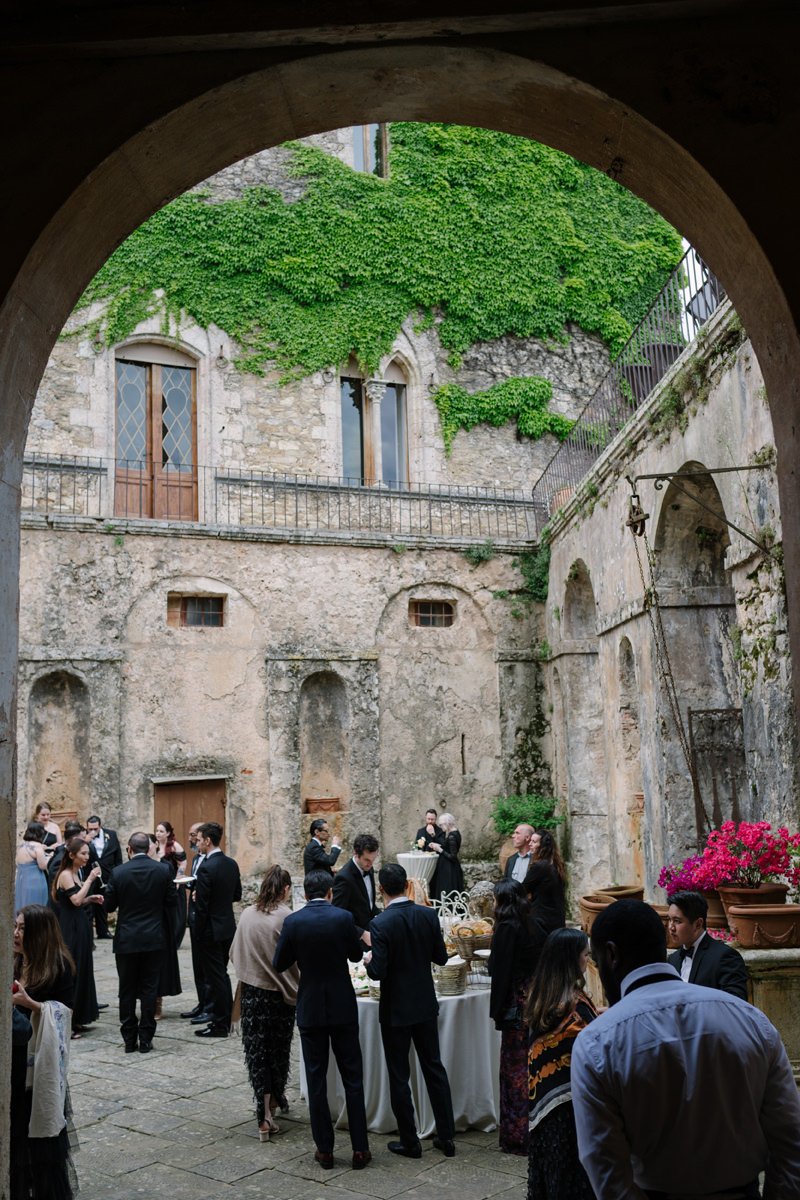 Guests enjoying aperitivo in the castle courtyard during a wedding at Castello di Celsa in Tuscany.