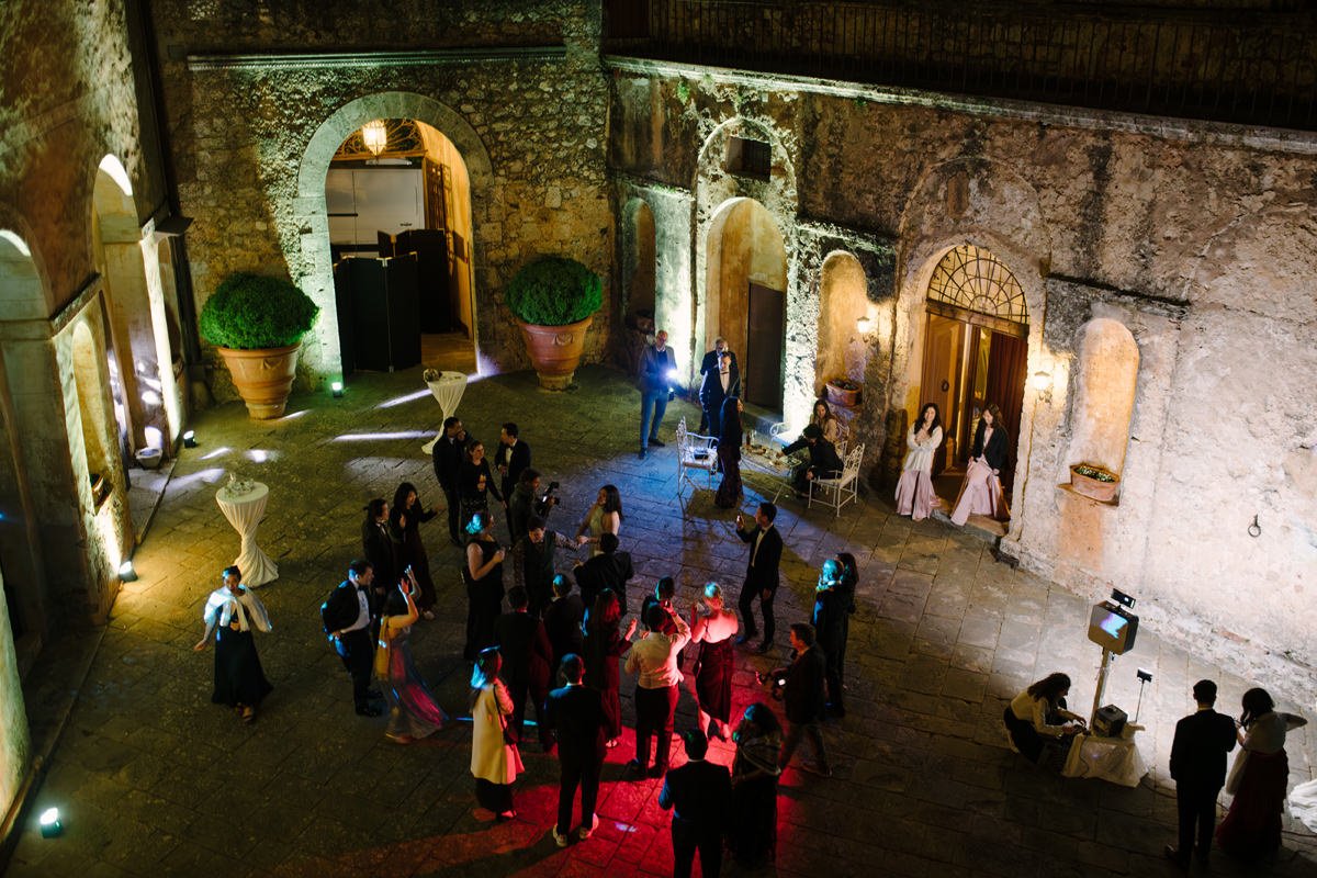 Wedding party inside the courtyard of Castello di Celsa with evening lighting and guests celebrating.