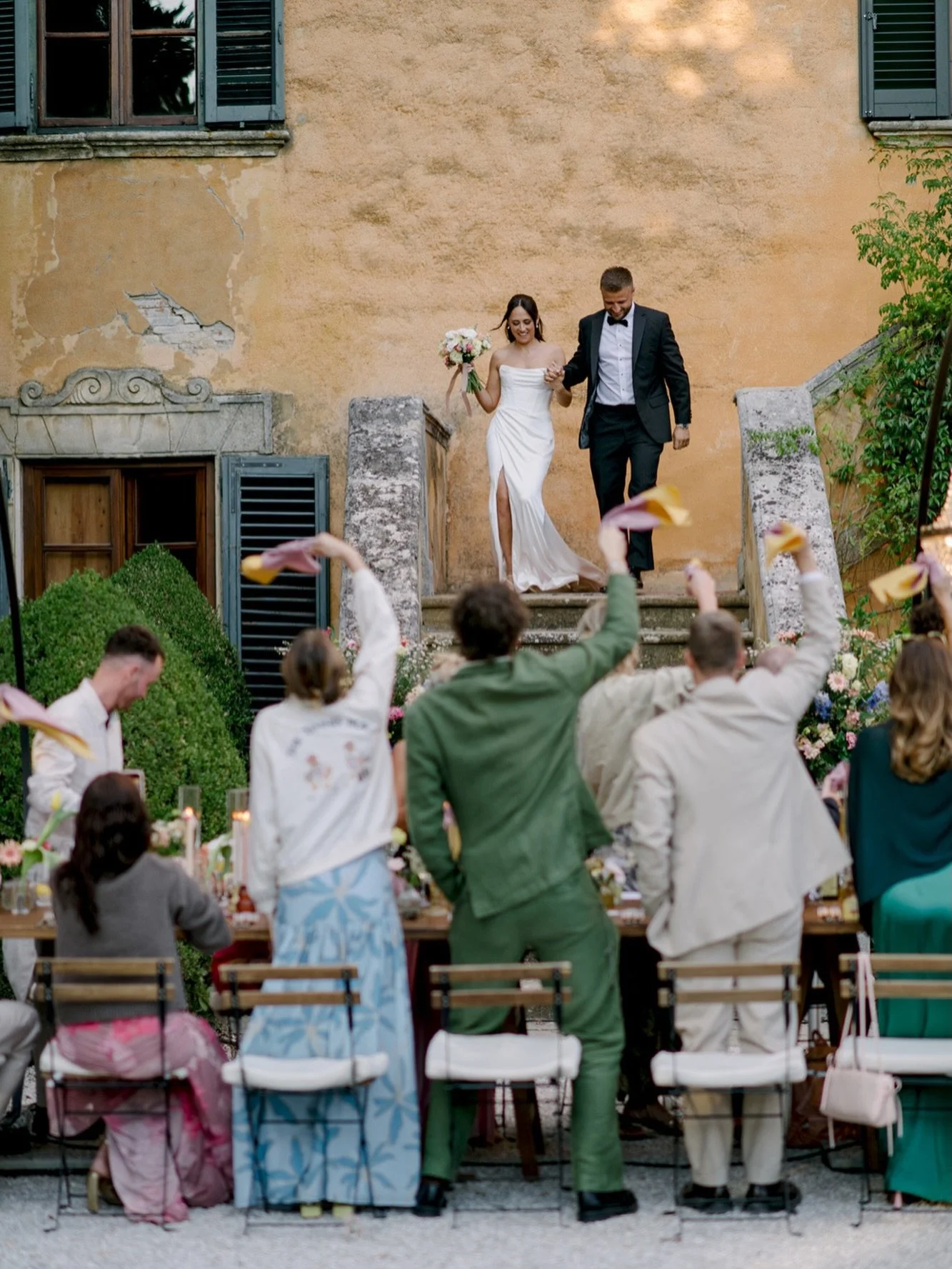 A wedding dinner entrance like this does not need much direction.

Just the couple holding hands, walking down the stairs, and a whole courtyard of guests cheering, waving handkerchiefs, and welcoming them into the evening. These are the moments I lo