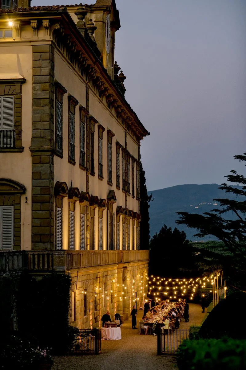 Torre a Cona wedding venue in Tuscany, a Renaissance estate surrounded by vineyards, olive groves, and landscaped gardens near Florence. Wedding dinner with long table under string lights.
