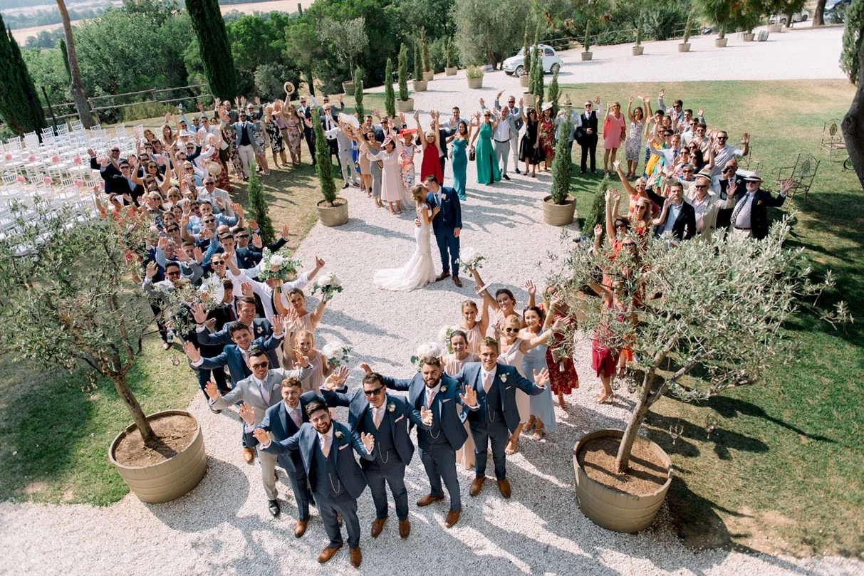 Wedding group forming a heart shape with the couple kissing in the center at Conti di San Bonifacio.
