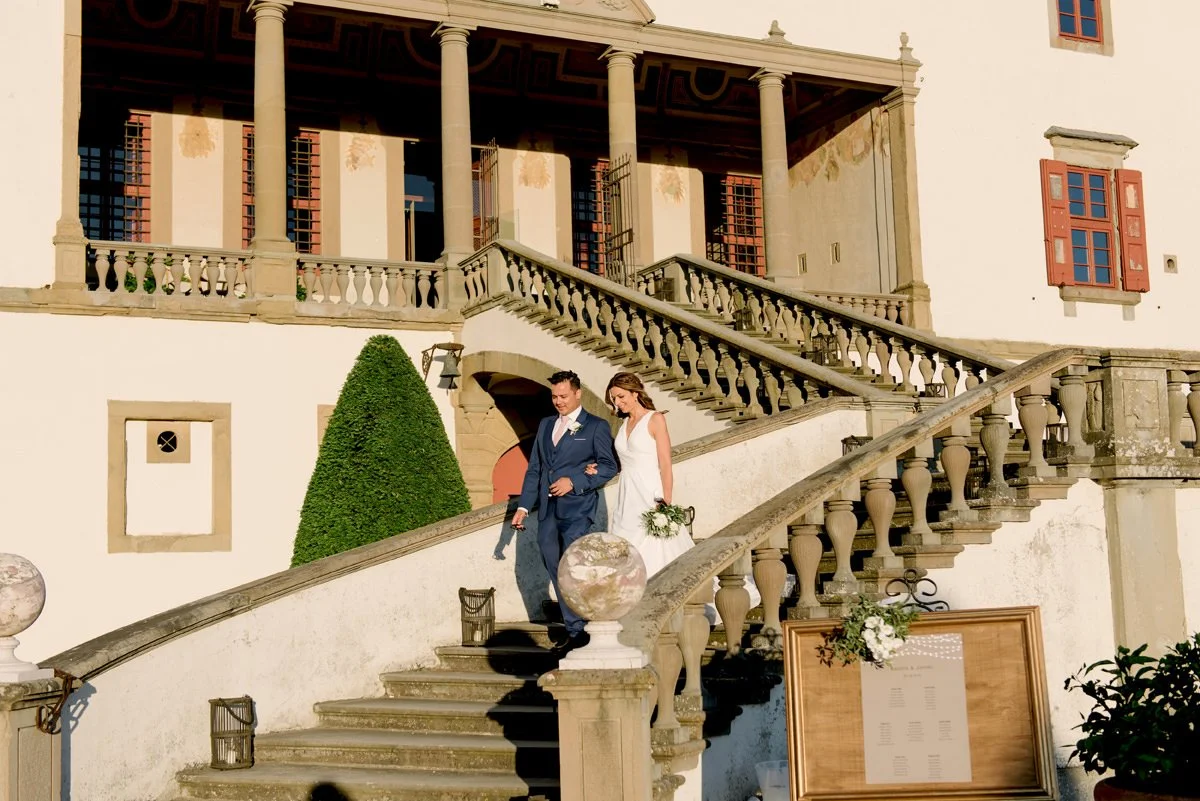 Wedding couple walking down the stairs of Villa Artimino toward their outdoor wedding dinner.