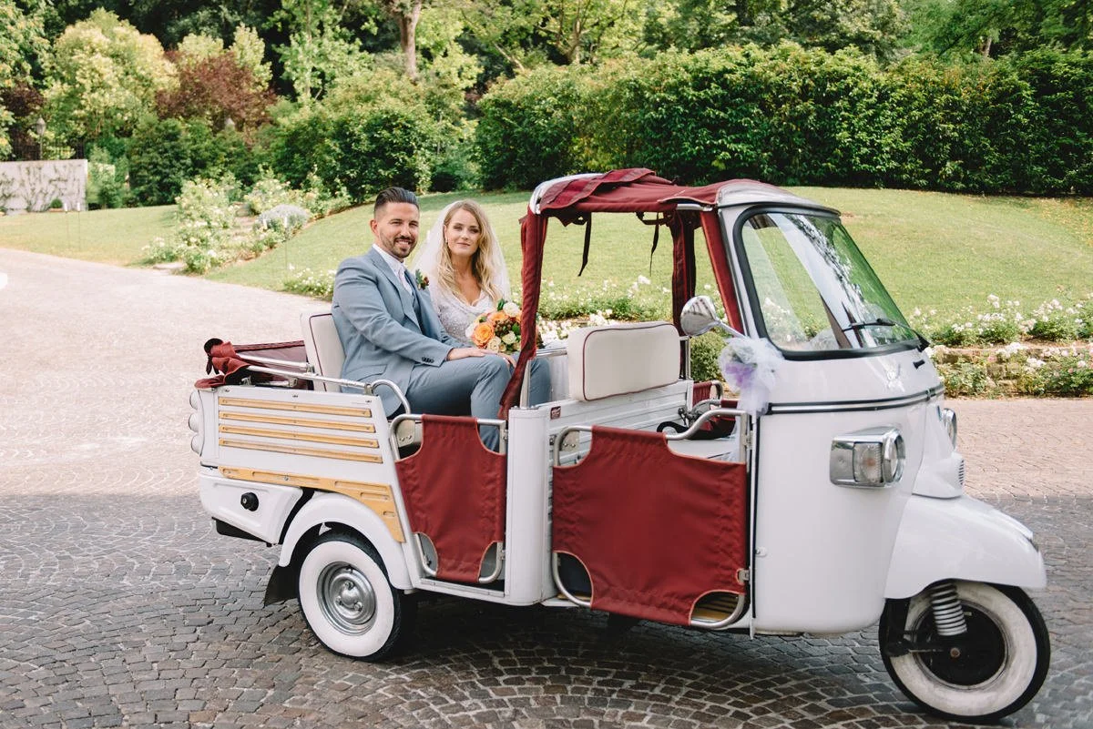 Wedding couple sitting in a vintage Piaggio cabrio at Villa Cora in Florence.