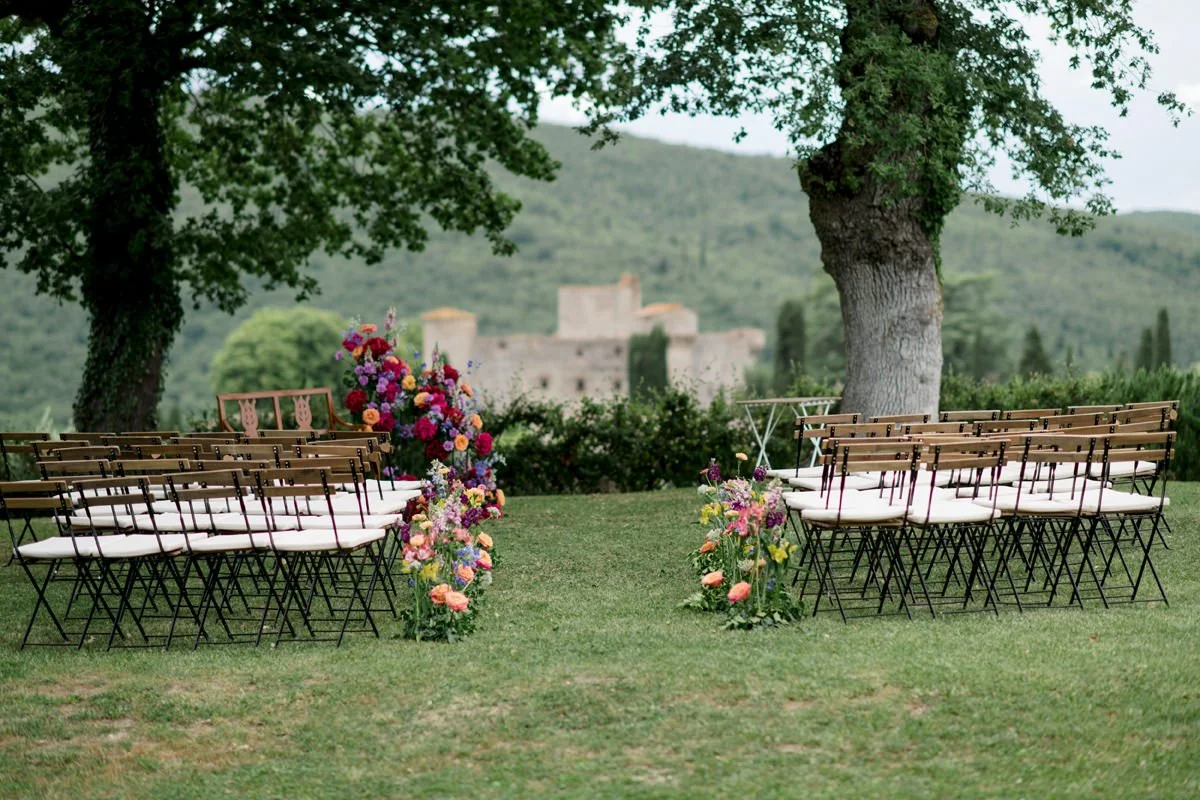 Wedding ceremony at Castello di Meleto with floral design, set against the castle backdrop and overlooking the Chianti countryside in Tuscany.