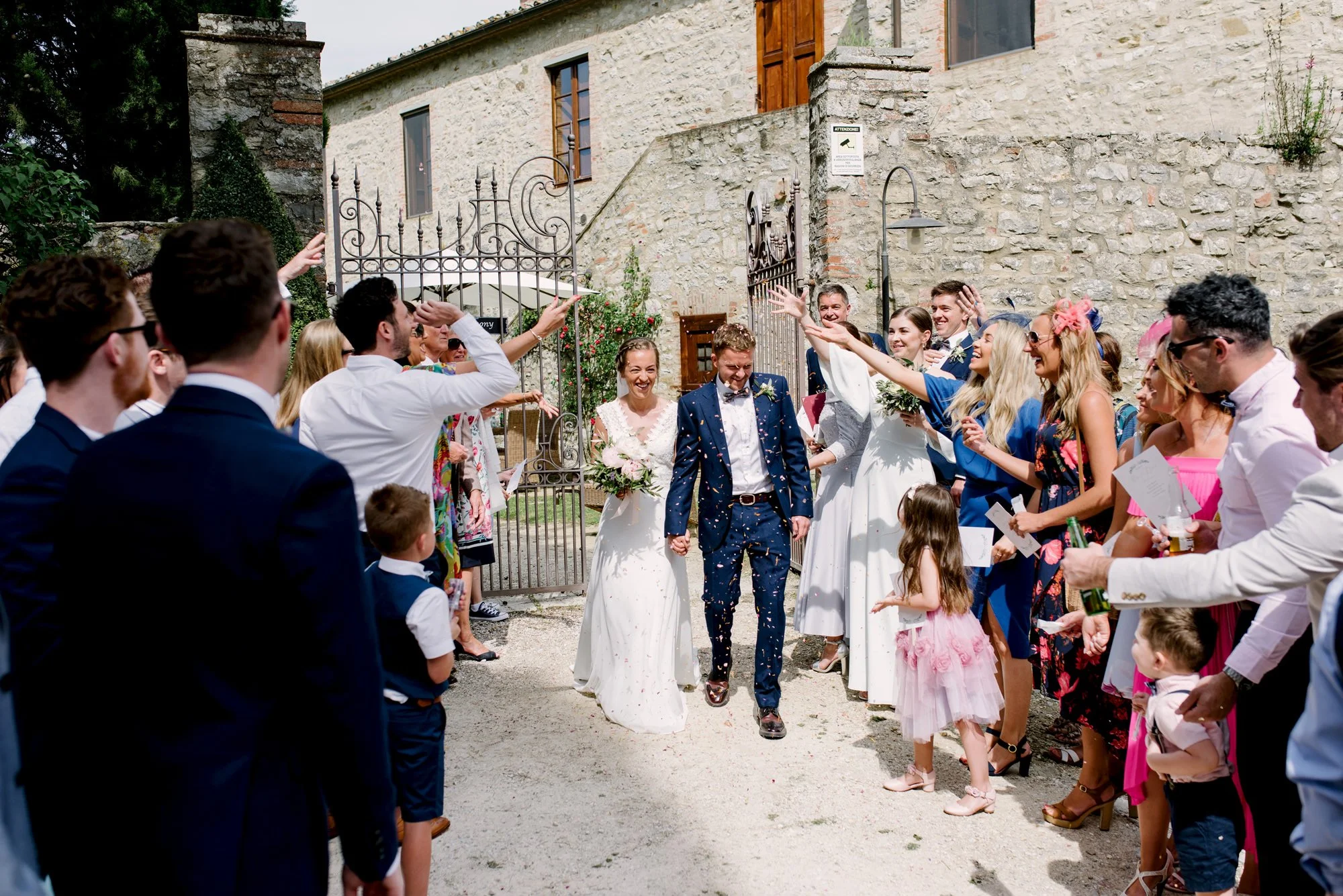 Bride and groom walking between guests throwing petals after their ceremony at Borgo Pietrafitta.