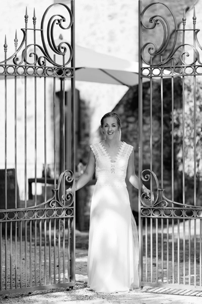 Black and white photo of the bride opening a gate during wedding preparations at Borgo Pietrafitta.