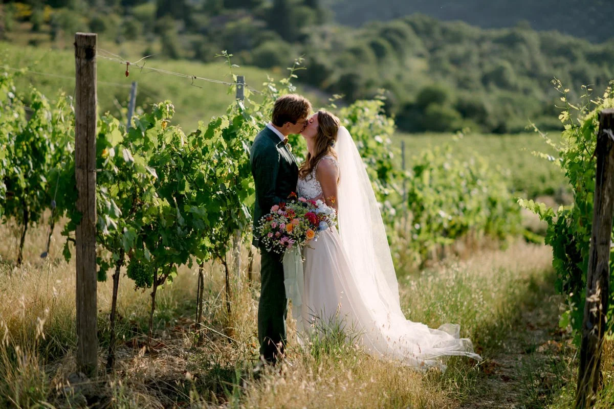 Bride and groom kissing among the vineyards at Le Filigare wedding venue in Tuscany.