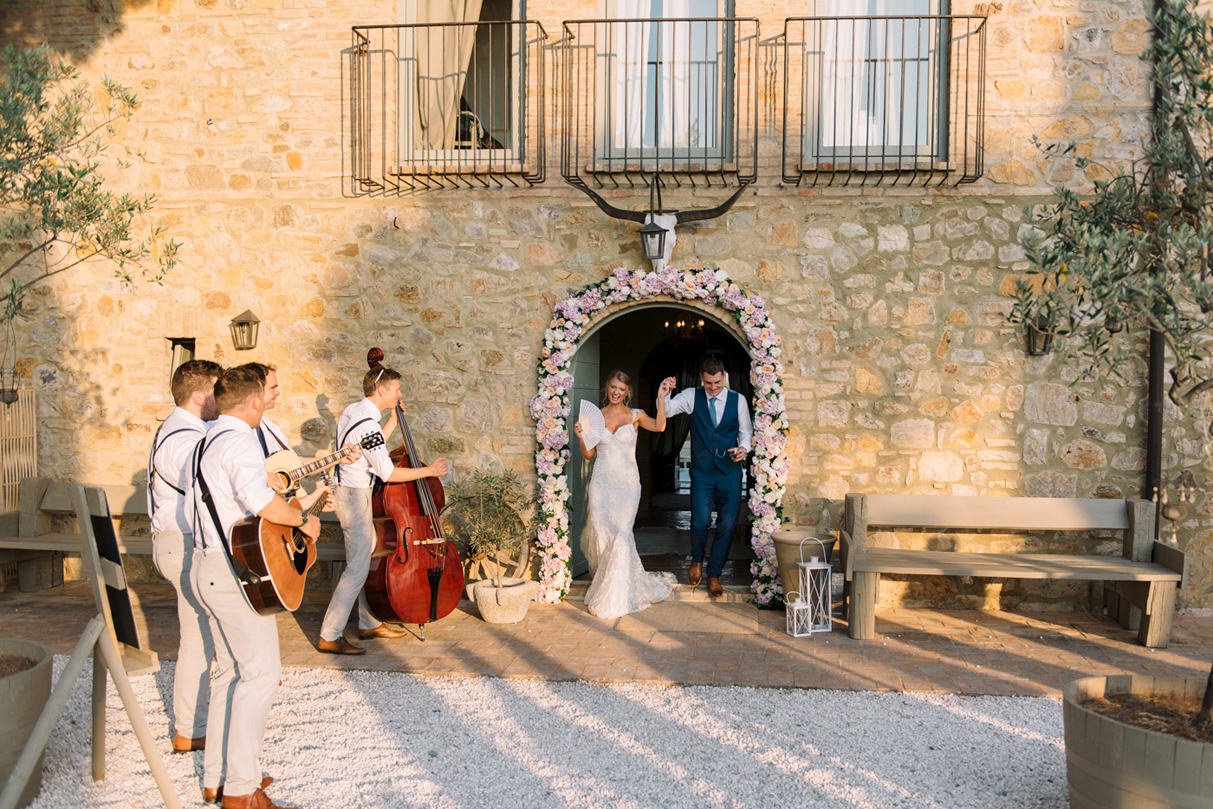 Wedding couple walking toward the dinner area with live band playing at Conti di San Bonifacio.