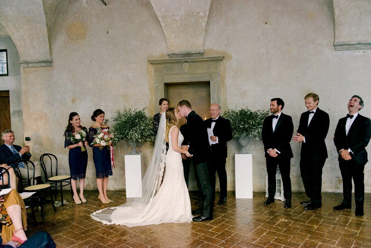 Bride and groom sharing their first kiss during the wedding ceremony at Castello di Montegufoni in Tuscany.