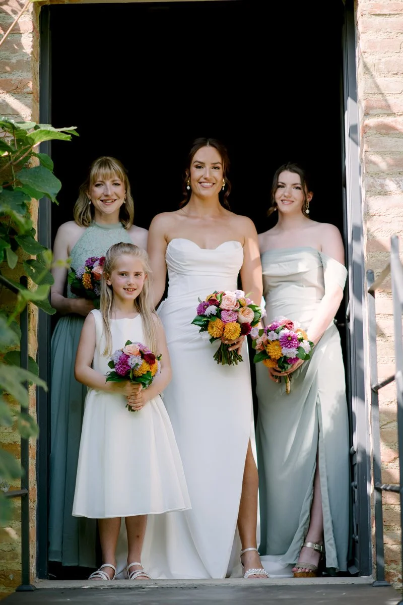 Bride and bridesmaids with a flower girl at the entrance of Casa Cornacchi, a countryside wedding venue in Tuscany