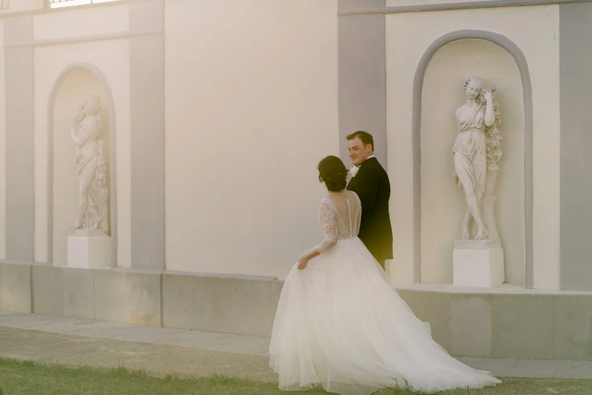 Couple walking beside historic garden statues during golden hour at Villa Hotel Tolomei in Florence.