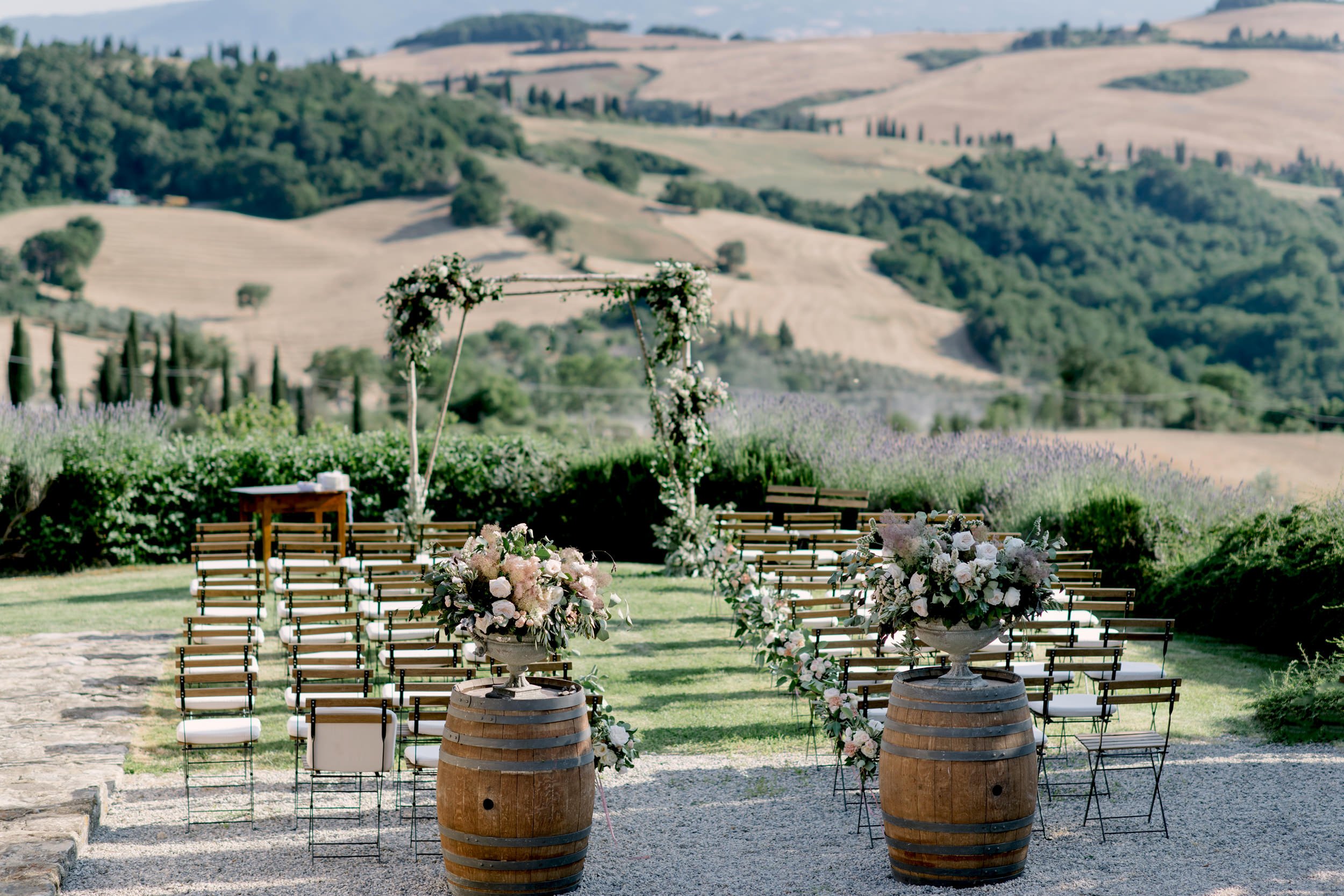 Wedding ceremony setup at Terre di Nano with floral arch and panoramic Val d’Orcia hill views.