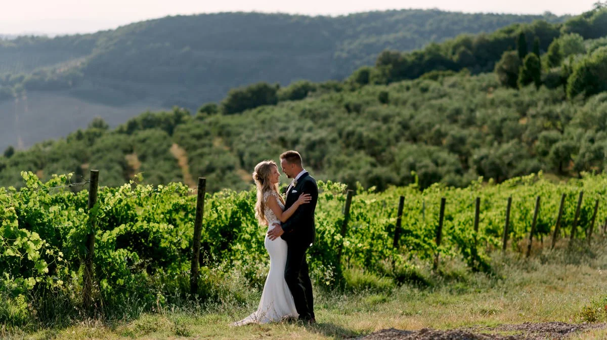 Couple standing close together in lush green vineyards at Terre di Nano wedding venue in Val d’Orcia.
