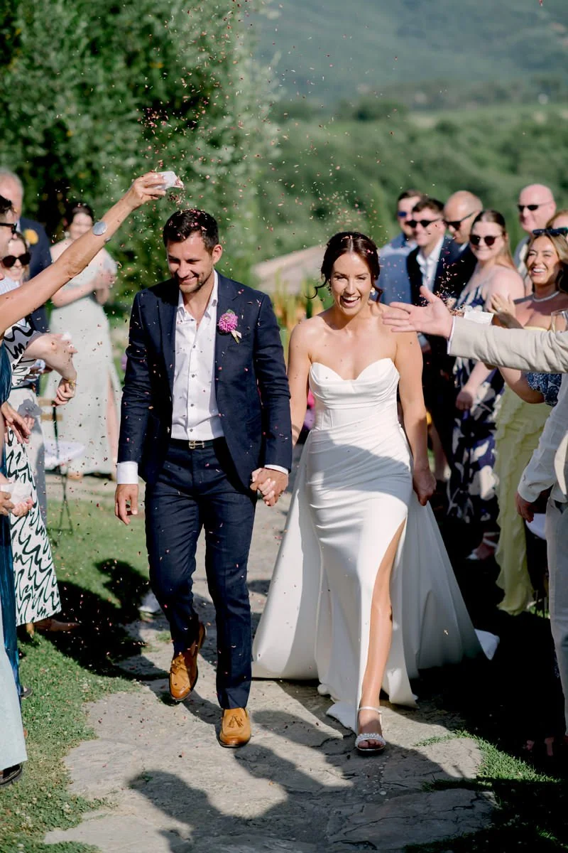 Couple walking after the ceremony at Casa Cornacchi as guests throw petals in the Tuscan countryside