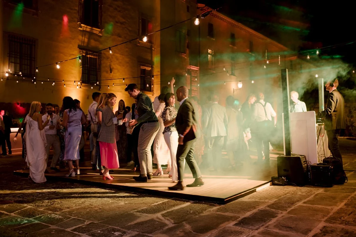 Wedding party behind the villa at Torre a Cona with a lively dance floor and strobe lighting at night.