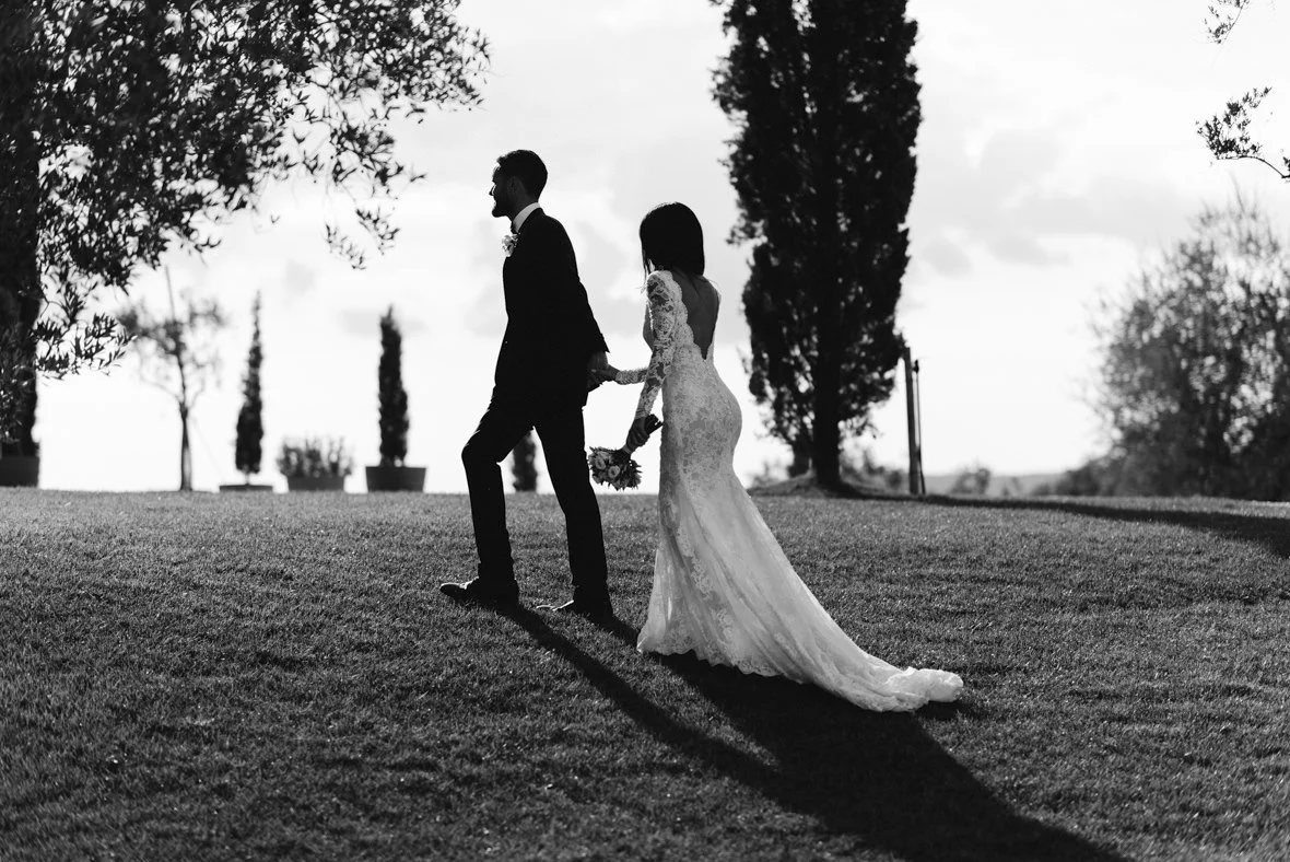 Black and white photo of a wedding couple walking together at Conti di San Bonifacio.