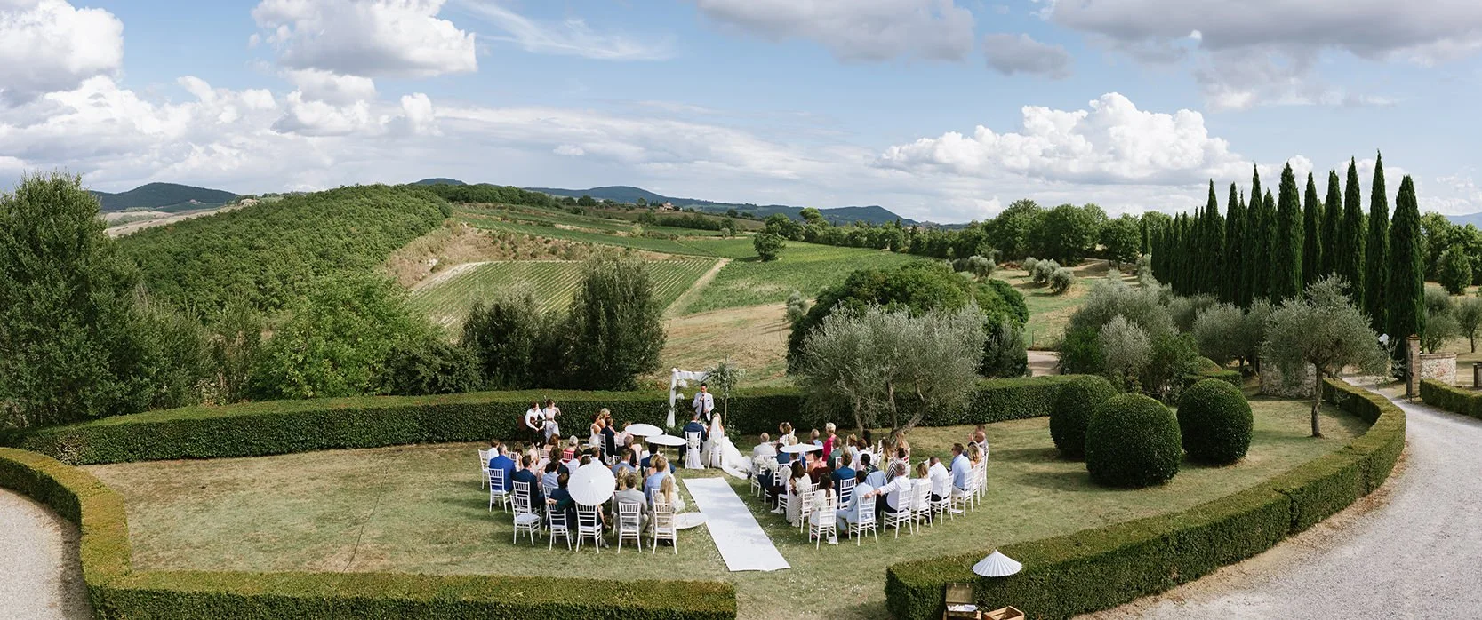 Wide view of the wedding ceremony at Villa Boscarello photographed from the terrace overlooking the celebration.