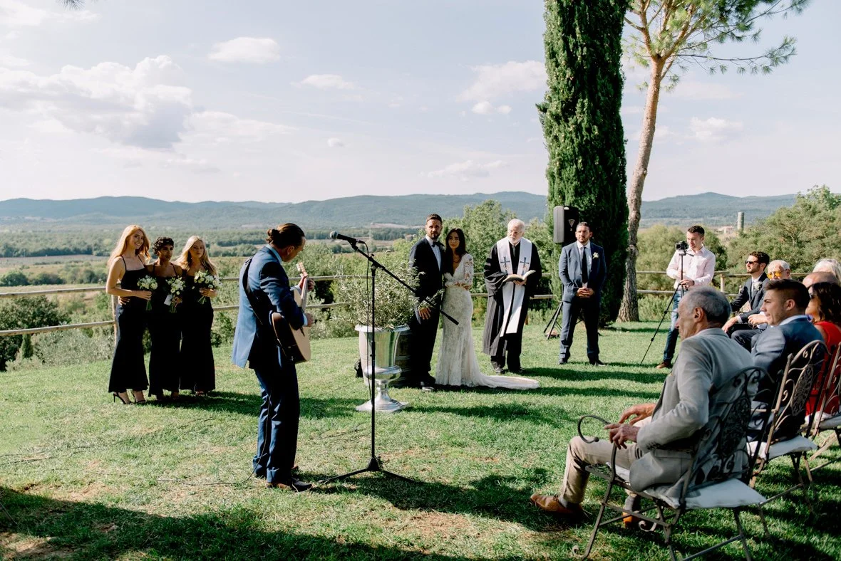 Wedding couple listening to live guitar music during their ceremony at Conti di San Bonifacio in Tuscany.