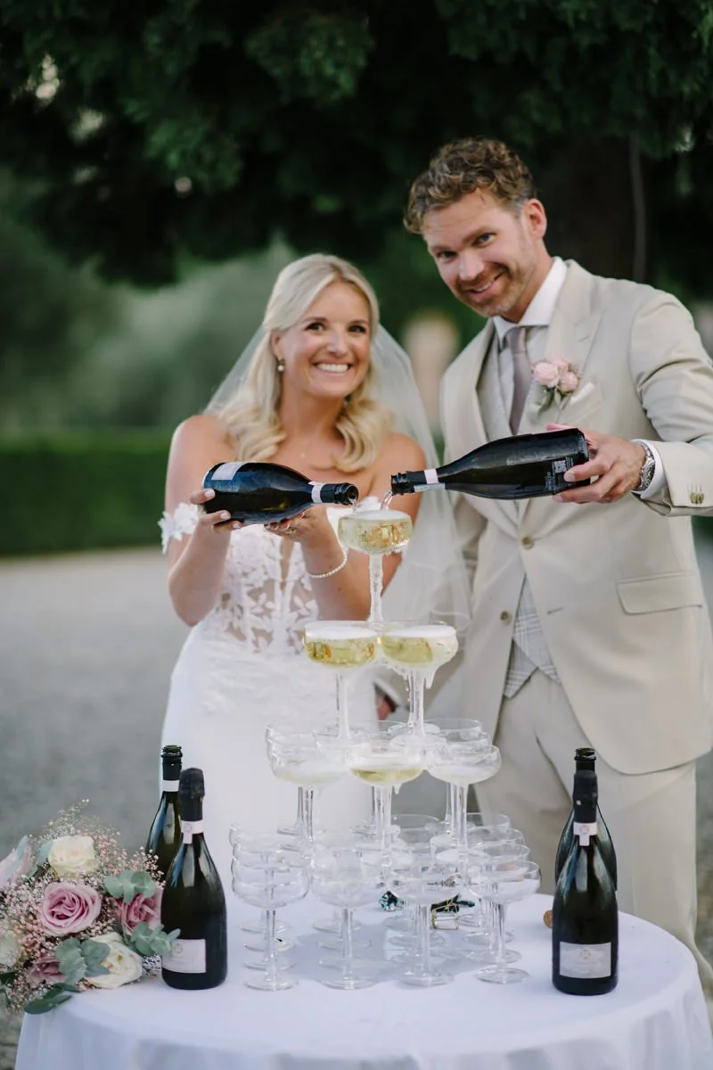 Bride and groom pouring prosecco into a champagne tower during their wedding celebration at Villa Boscarello.
